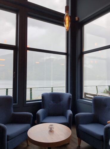A vertical shot of armchairs around the table behind the windows